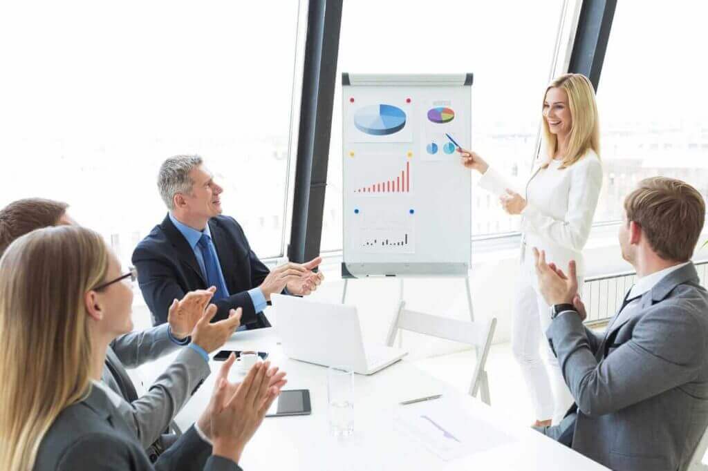 A group of business people clapping in front of a whiteboard