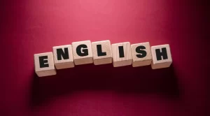 Wooden blocks spelling "ENGLISH" are arranged on a red background.