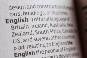 Close-up of a dictionary page showing the definition of "English" as an official language in various countries and its adjective form relating to England.