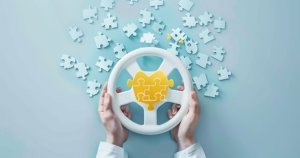 Hands holding a steering wheel shaped puzzle with interlocking pieces on a light blue background.