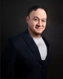 A man in a black suit posing for a photo.