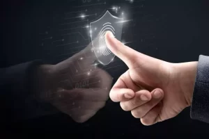 A hand pressing a virtual fingerprint scanner icon with a shield symbol on a digital interface background.