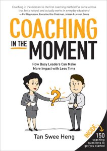 Book cover for "coaching in the moment: how busy leaders can make more impact with less time" by tan swee heng featuring two illustrated professionals exchanging a lightbulb with a question mark inside it.