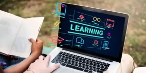 Person holding a book sits beside another person using a laptop displaying the word "LEARNING" with education-related icons.