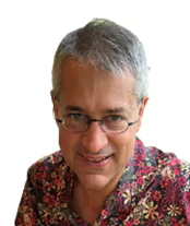 A middle-aged person with short gray hair and glasses, wearing a colorful patterned shirt, smiling at the camera against a white background.