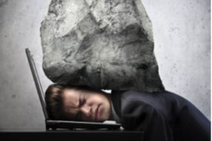 Person with a large rock pressing down on their head while using a laptop.