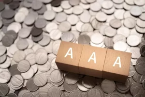 Scattered silver coins with three wooden blocks displaying the letter "A" on top.